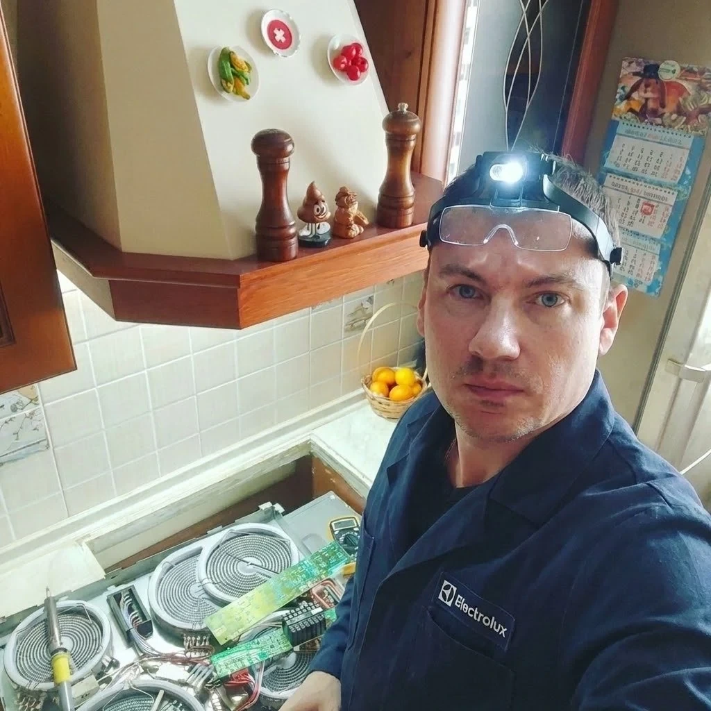 Сервисный инженер Антон Черняев ремонтирует варочную панель на кухне клиента
